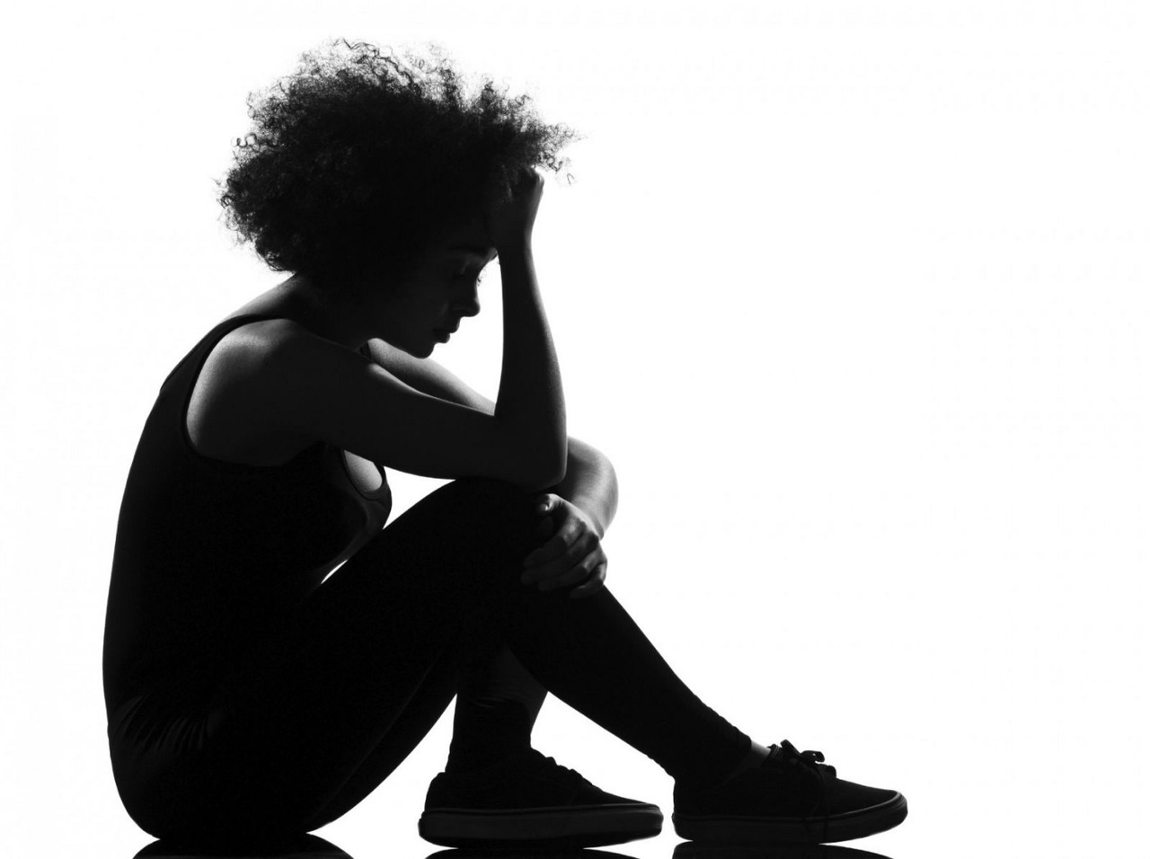 a black woman seated and looking down, facing to our right, in black and white