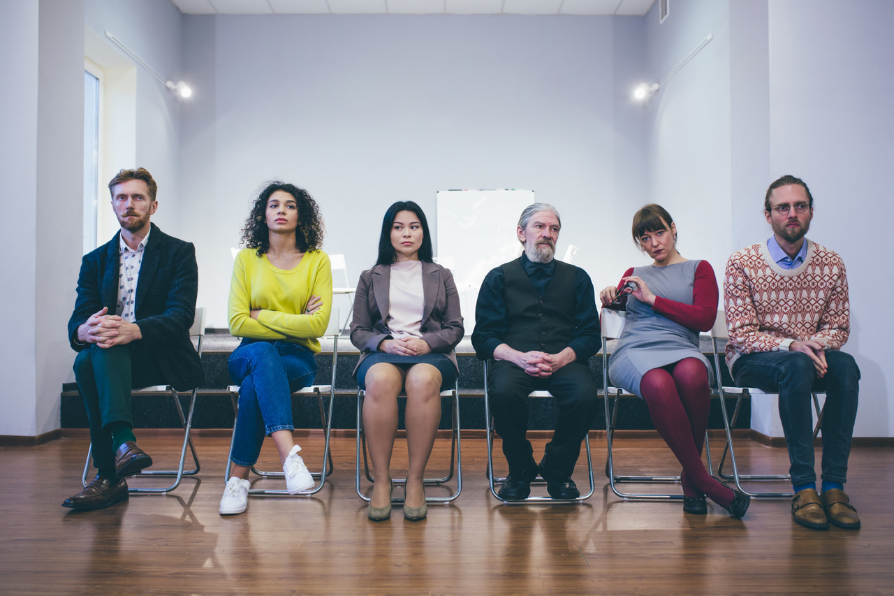 a row of people seated, all looking uncomfortable