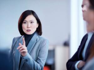 Asian woman speaking and holding her hand up