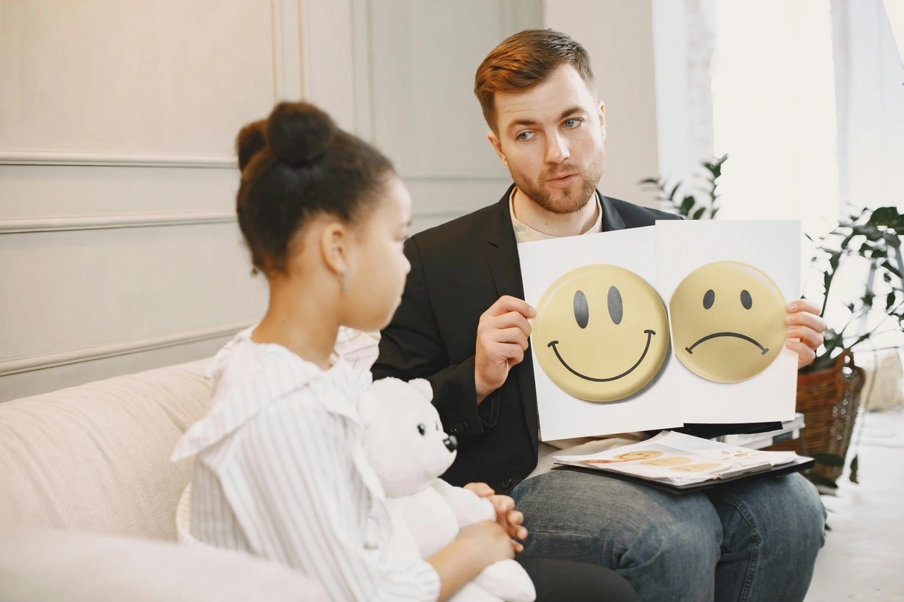 the adult white male holding emoji cards with the little girl